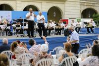 El concejal de Cultura y el director de la Banda, en el escenario, con el compositor de pie entre el público , 