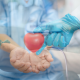 Imagen de persona donando sangre y dos manos sujetando corazón rojo